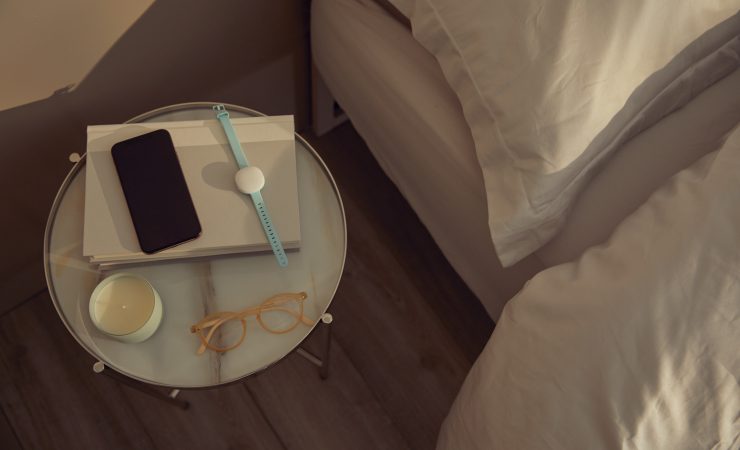 An Ava bracelet and smartphone on a bedside table. Image: COVID-RED