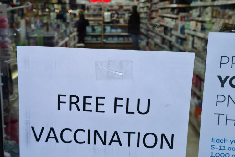 Photo of a poster in a pharmacy windown announcing free vaccine shots. By  Yau Ming Low via Shutterstock