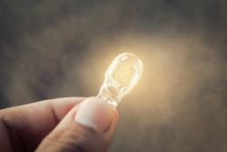 Close up of a hand holding a tiny lightbulb. Credit: Shutterstock