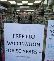 Photo of a poster in a pharmacy window announcing free vaccine shots. By  Yau Ming Low via Shutterstock